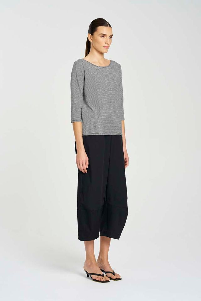Woman wearing a gray striped sweater and black wide-leg pants on a white background